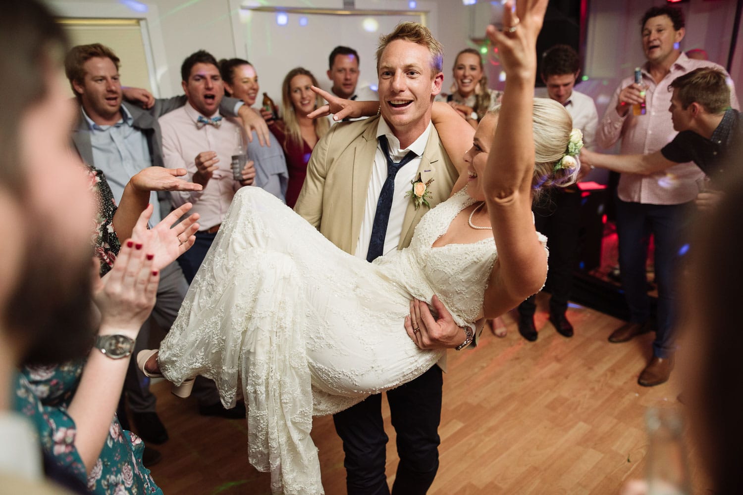 Groom carrying bride at their wedding reception