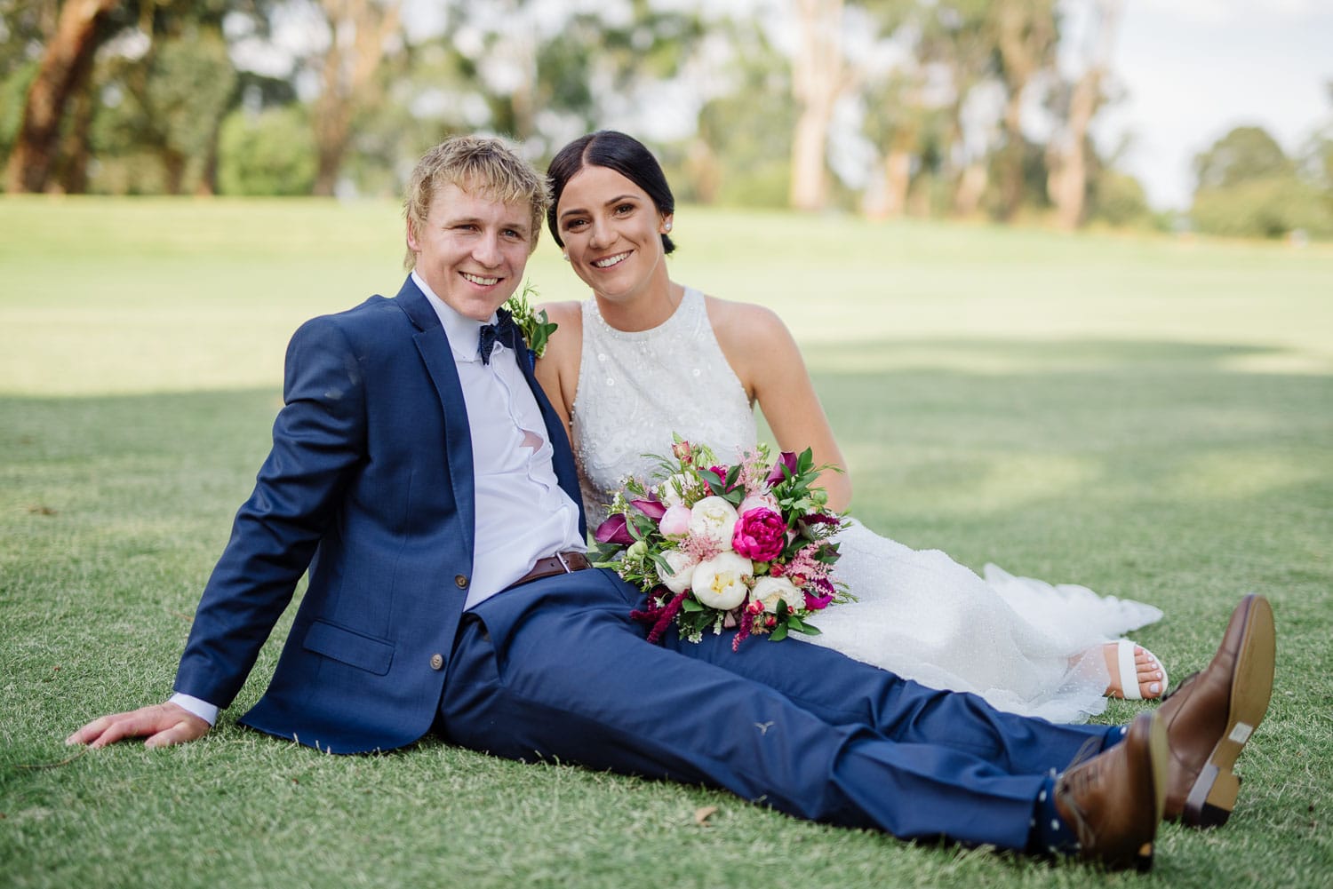 Bride and groom relax on the grass at Colac golf club