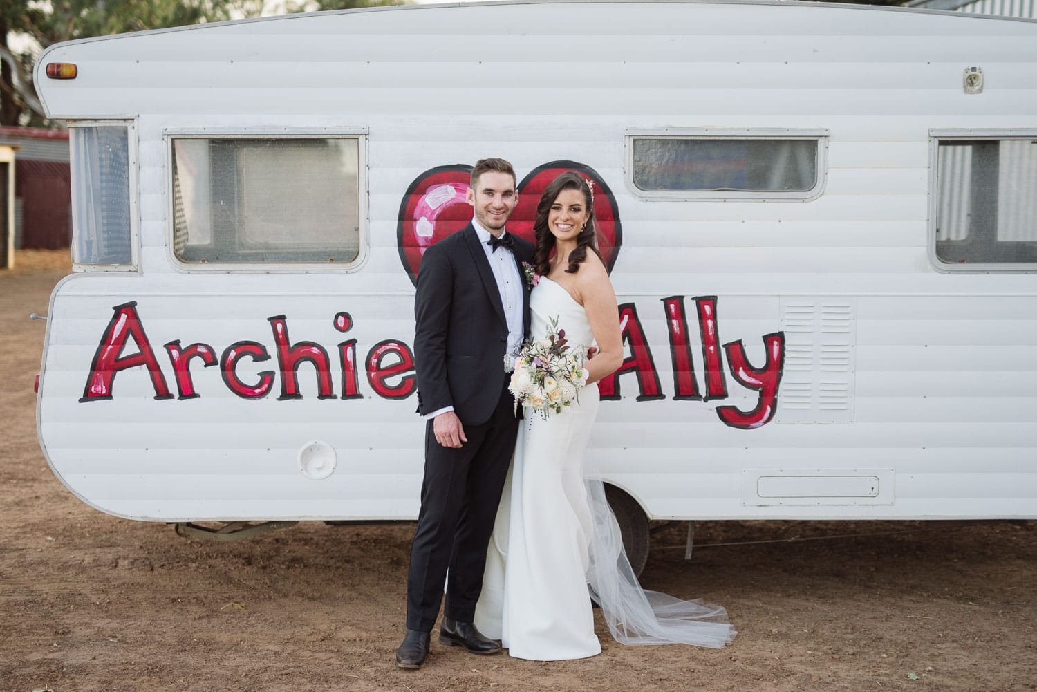 Archie and Ally in front of a custom painted caravan