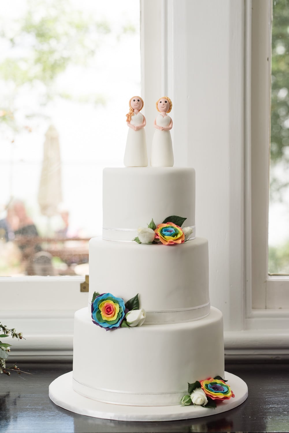 Same sex wedding cake with rainbow flowers