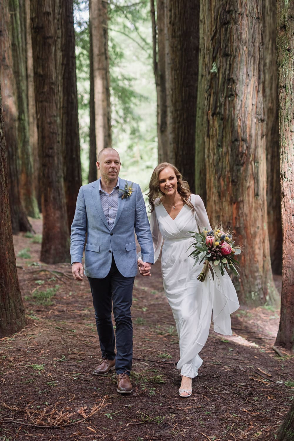Bride and groom walk down the aisle together in the redwoods