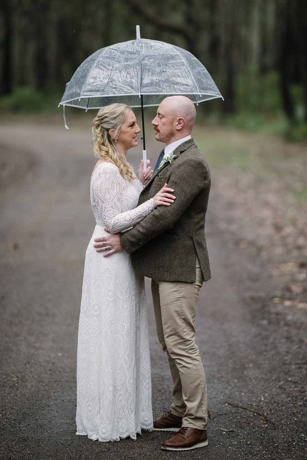 Bride and groom in the rain under an umbrella